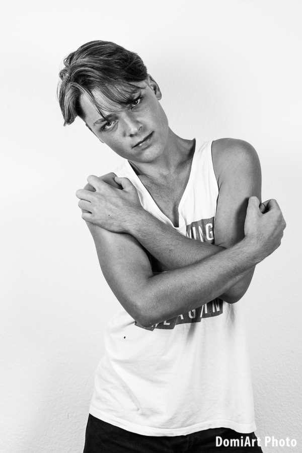 férfi portfólió fotózás fekete hajú fiú, vállal a falnak támaszkodva