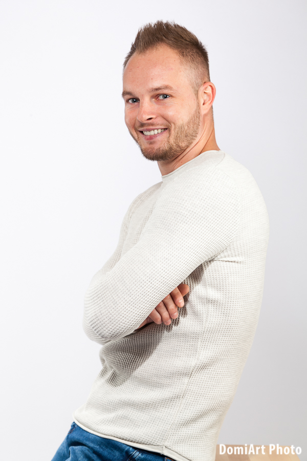 nevető srác karbatett kézzel néz a kamerába egy széken ülve, férfi fotózás Debrecen