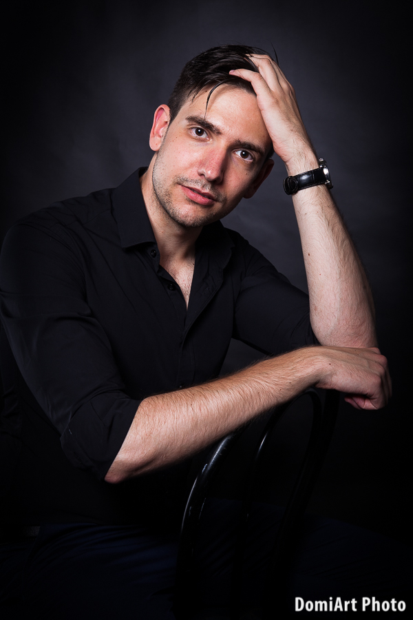 férfi modell portfólió - közeli portré fekete háttérrel, fekete ingben, kibombolva