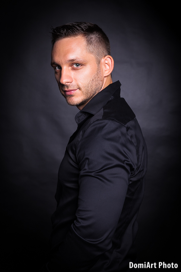 Férfi portré, fekete háttérrel kicsit visszaforduló tekintet, kis mosoly