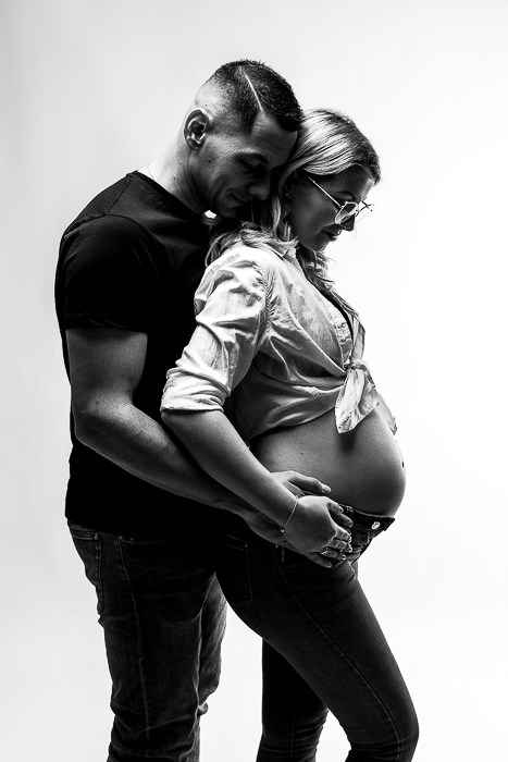 kontrasztos fényben fotózott kismama fotózás, apuka hátulról ölel, anyuka a hasára néz le, meghitt és intim fotó - kismama fotózás debrecen