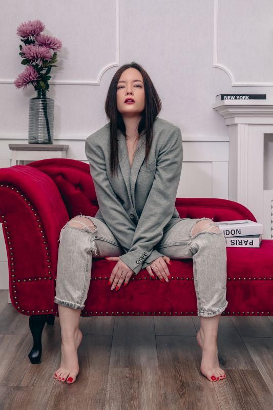 könyvek előtt virágokkal a kezében gogol egy lány hosszú szürke kabátban a lifestyle fotózáson