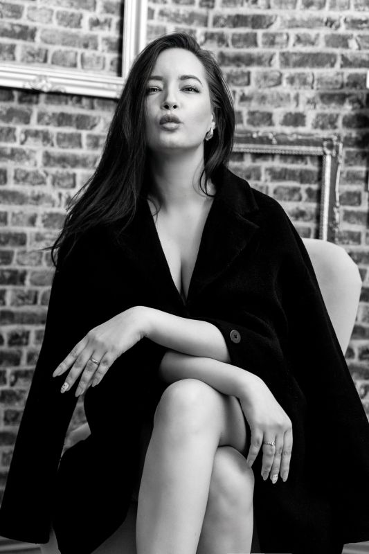 velünk szemben ül a hölgy a fotalban, vállán fekete kabát, alatta csak fehérnemű - lifestyle glamour fotózás