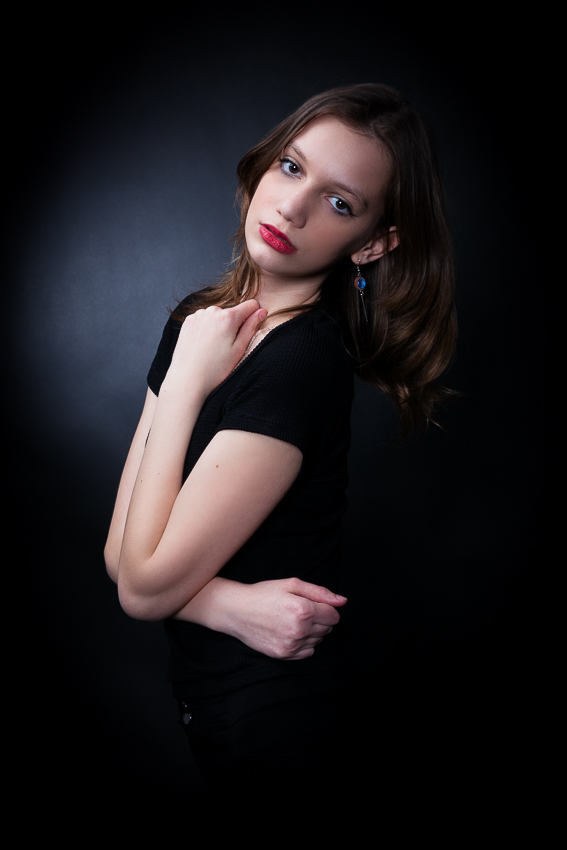 modell portfólió készítés fekete harisnya és fekete body a modellen, görnyedt pózban a fekete széken ül, fekete háttér előtt - debrecen