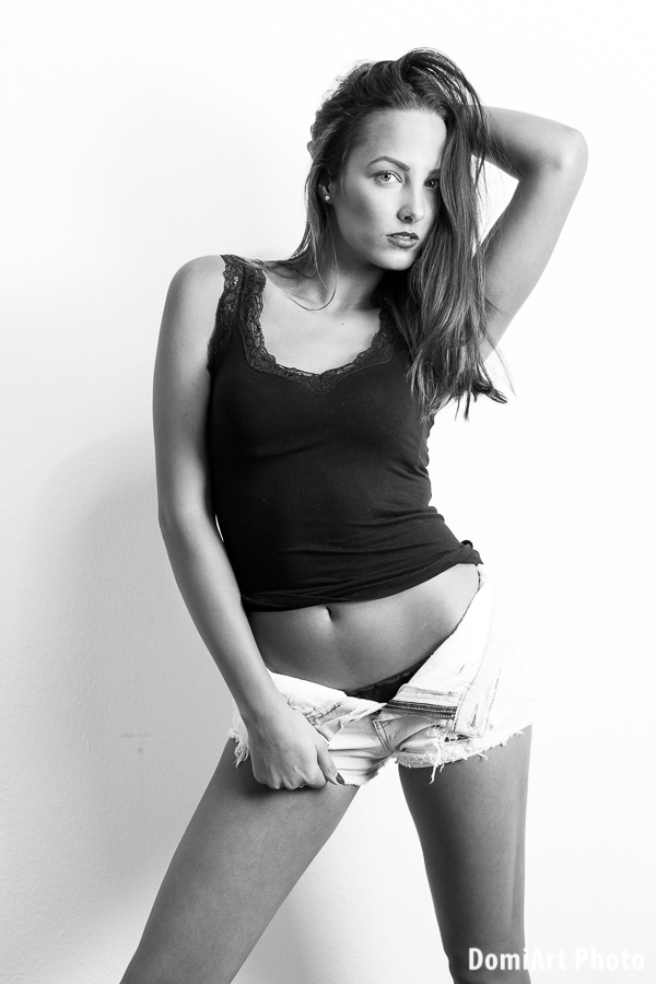 modell rövid kigombolt farmer nadrágban pózol fal mellett szenvedélyes nézéssel - modell portfólió debrecen