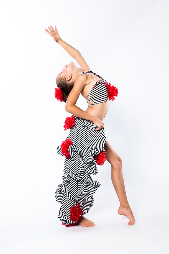 csodaszép spanyolos ruhában pózol a kis 6 éves kislány táncos pózban, a kezét magasba emelve, maga felé tekintve - táncos fotózás debrecen